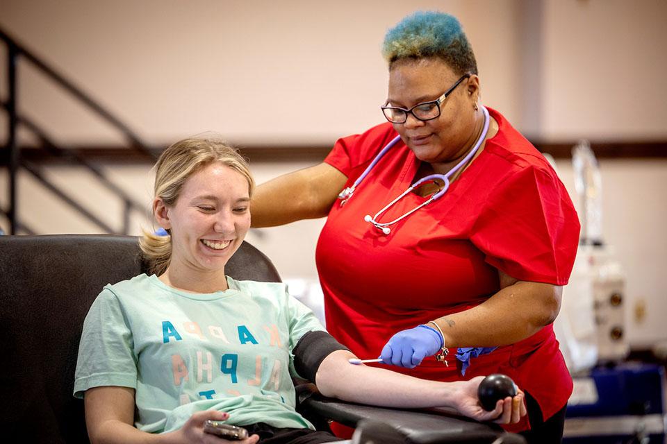在社会行动中心举办的献血活动中，一名学生在准备抽血时挤压压力球.