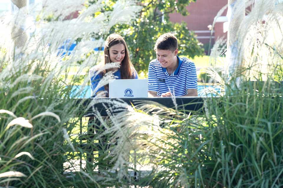 两个学生在凉亭玩笔记本电脑